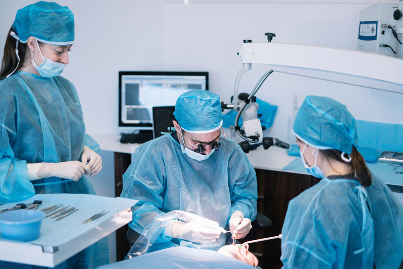 photo of a dental surgeon doing a live dental implant surgery procedure